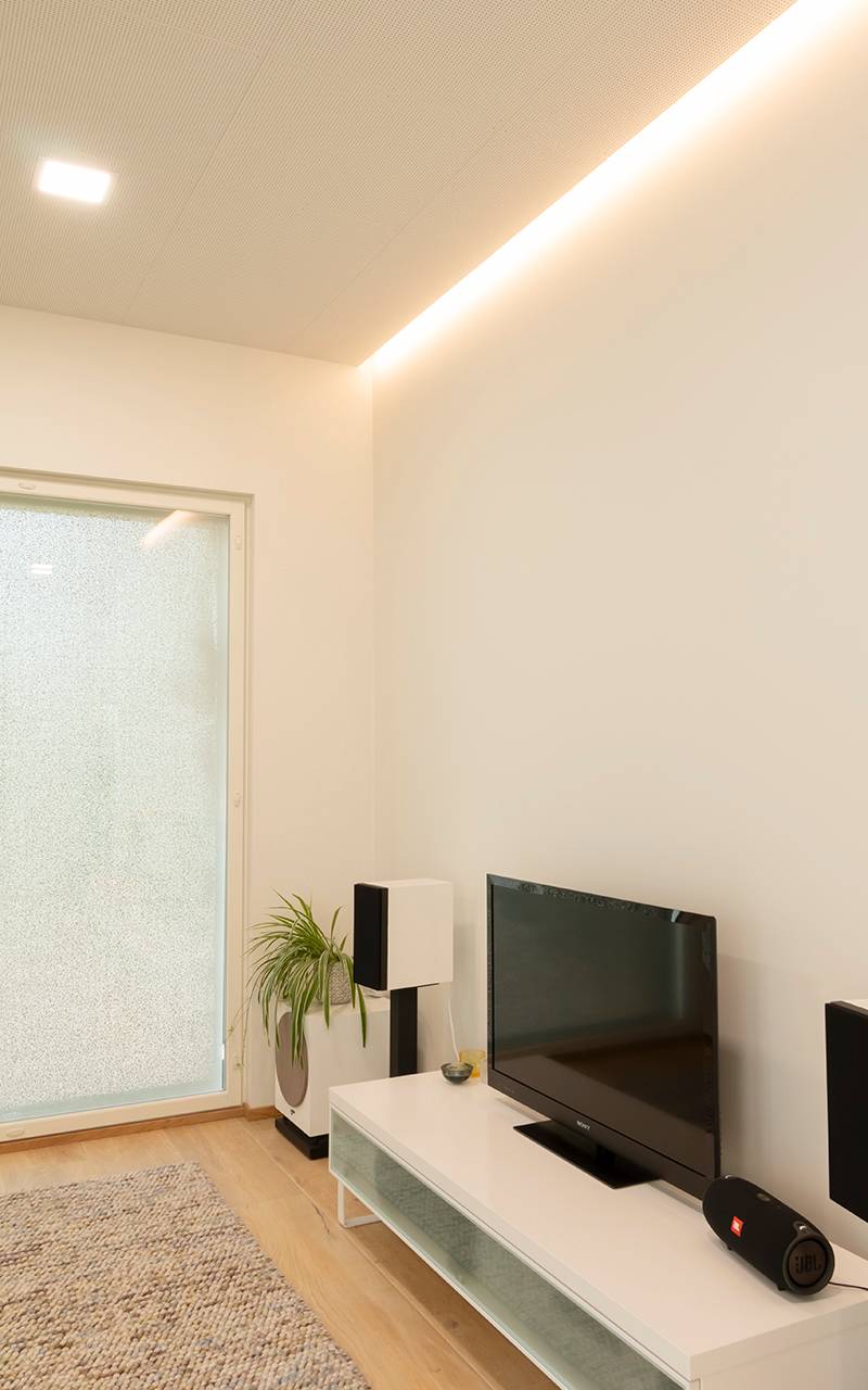 Bande lumineuse à leds au plafond et petit panneau lumineux à leds dans le salon.